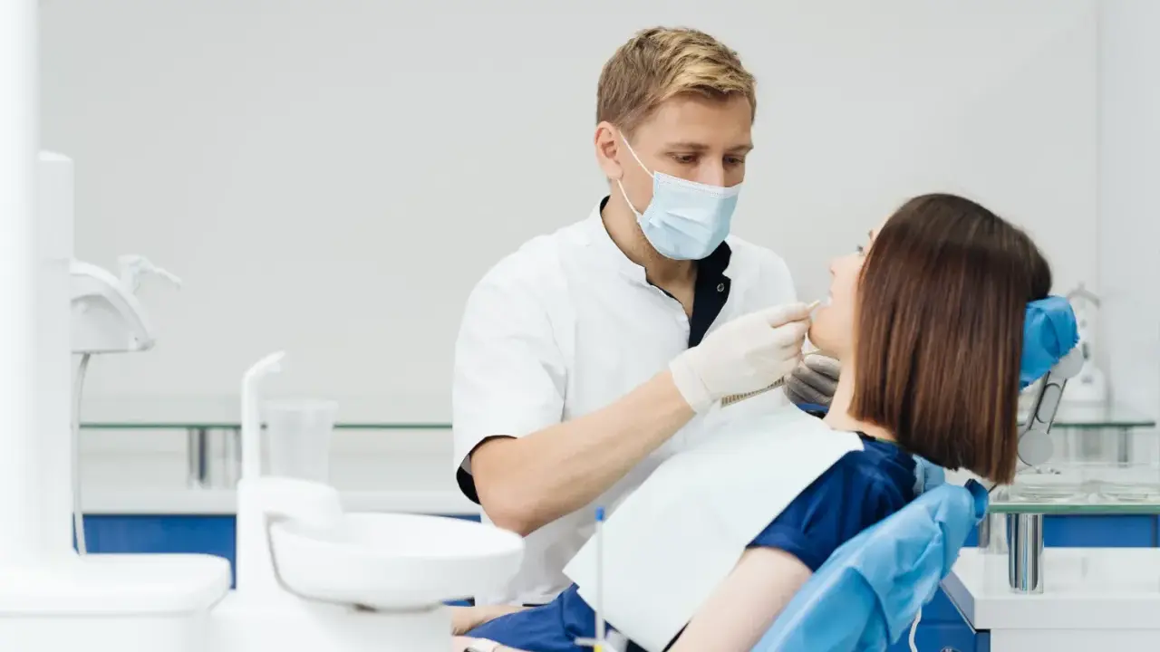 Dentysta wykonuje fluoryzację u pacjentki, dbając o zdrowie jej zębów.