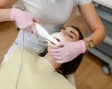Dentysta wykonuje higienizację zębów pacjentki. Widoczny skaner do cyfrowego wycisku zębów.