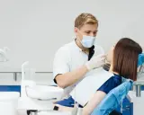 Dentysta wykonuje fluoryzację u pacjentki, dbając o zdrowie jej zębów.