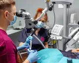 Stomatolog z mikroskopem precyzyjnie usuwa próchnicę z zęba pacjenta.