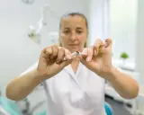 Lekarka łamie papierosa, sugerując, że po wyrwaniu zęba nie można palić.