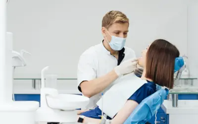 Dentysta wykonuje fluoryzację u pacjentki, dbając o zdrowie jej zębów.