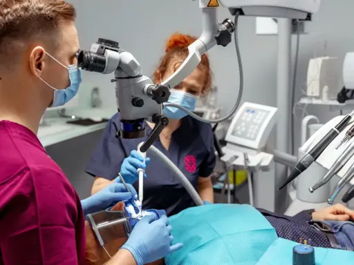 Stomatolog z mikroskopem precyzyjnie usuwa próchnicę z zęba pacjenta.