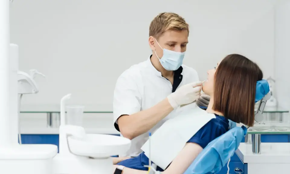 Dentysta wykonuje fluoryzację u pacjentki, dbając o zdrowie jej zębów.