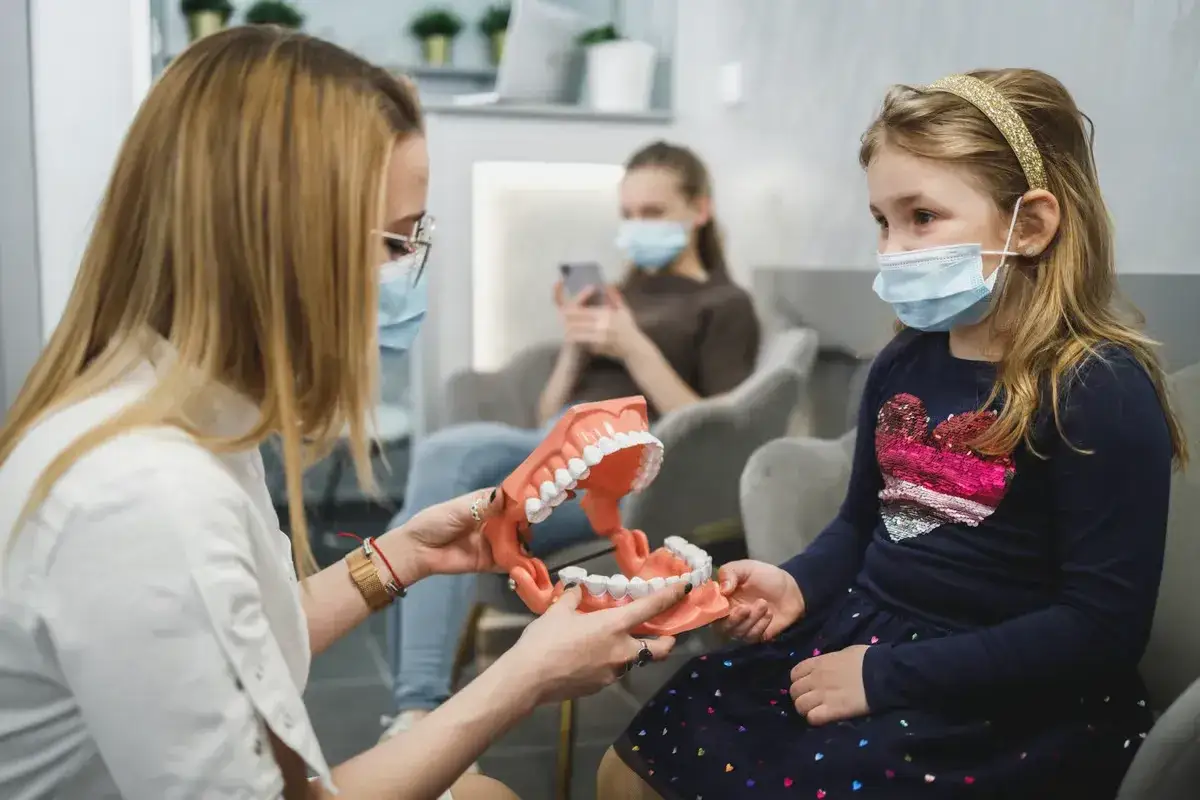 Ortodontka pokazuje model szczęki dziecku, wyjaśniając jak działa aparat ortodontyczny NFZ.