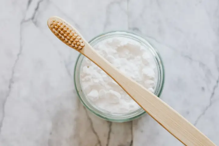 Naturalne usuwanie kamienia nazębnego w domu: bambusowa szczoteczka i soda oczyszczona.