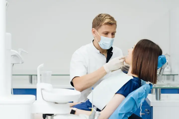 Dentysta wykonuje fluoryzację u pacjentki, dbając o zdrowie jej zębów.